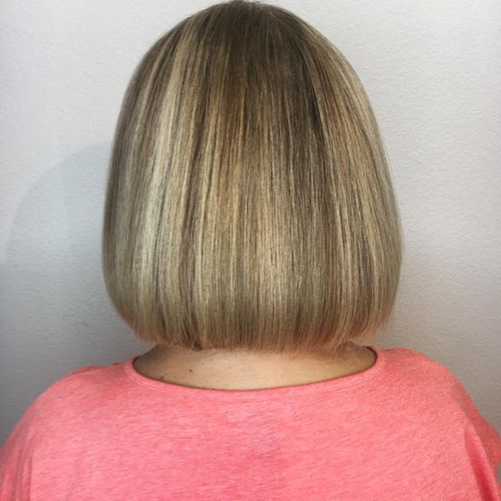 A blunt chin-length bob in blended blonde tones, seen from behind
