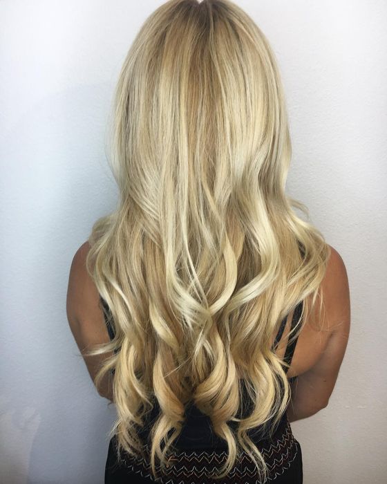 Long, bright blonde hair in soft curls, seen from behind