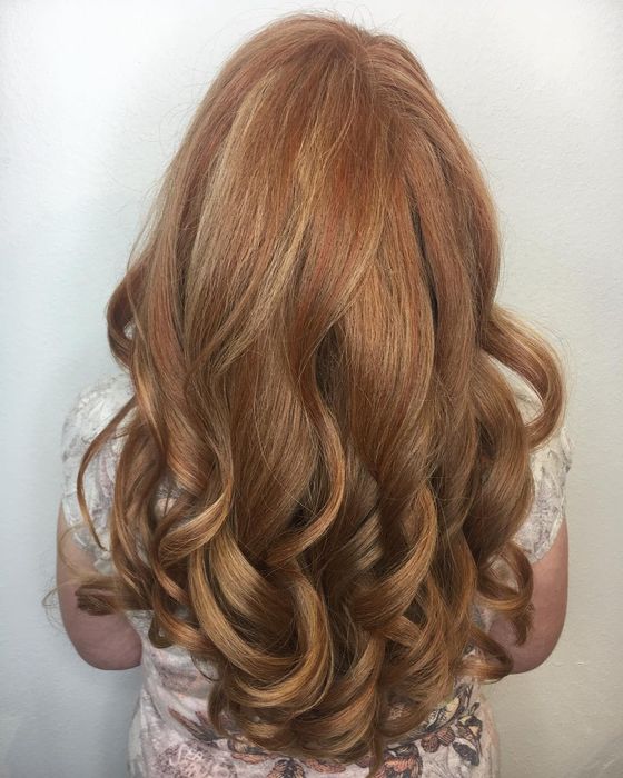 Long copper hair styled in loose, glossy curls, seen from behind